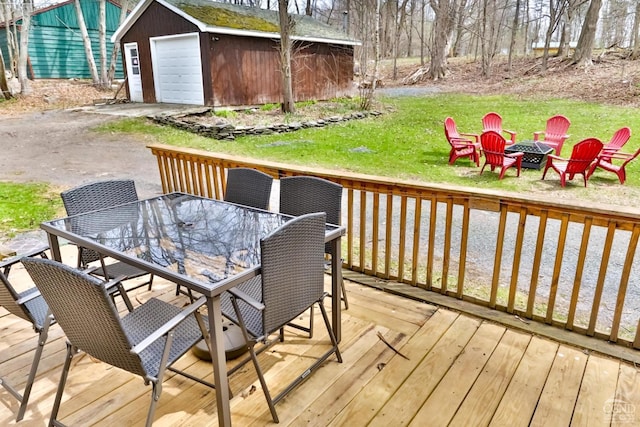 wooden deck with an outbuilding, a garage, and an outdoor fire pit