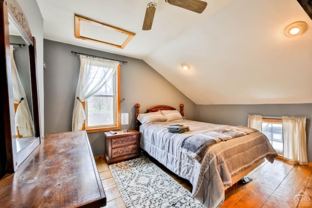 bedroom featuring multiple windows, light hardwood / wood-style flooring, vaulted ceiling, and ceiling fan