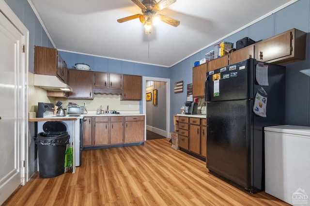 kitchen featuring black fridge, crown molding, sink, and light wood-type flooring