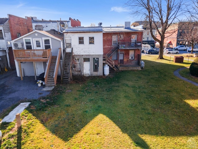 back of property with a wooden deck and a lawn