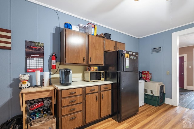 kitchen featuring black fridge, light hardwood / wood-style flooring, and ornamental molding