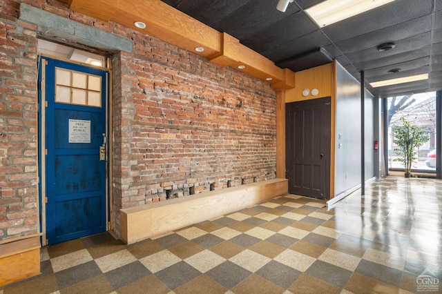 foyer featuring brick wall