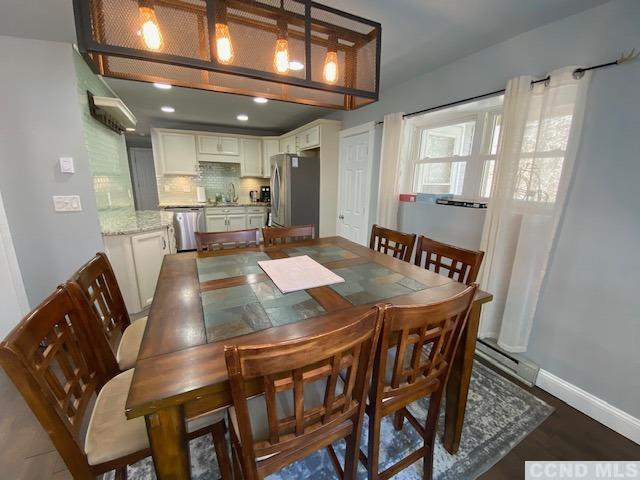 dining space featuring sink, dark wood-type flooring, and a baseboard radiator