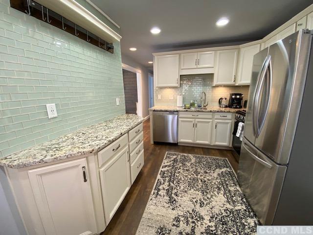 kitchen featuring white cabinets, light stone counters, dark hardwood / wood-style flooring, and stainless steel appliances