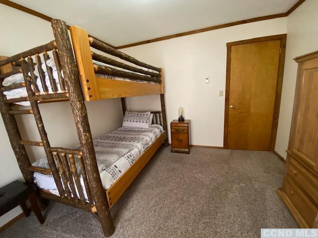 bedroom with ornamental molding and dark colored carpet