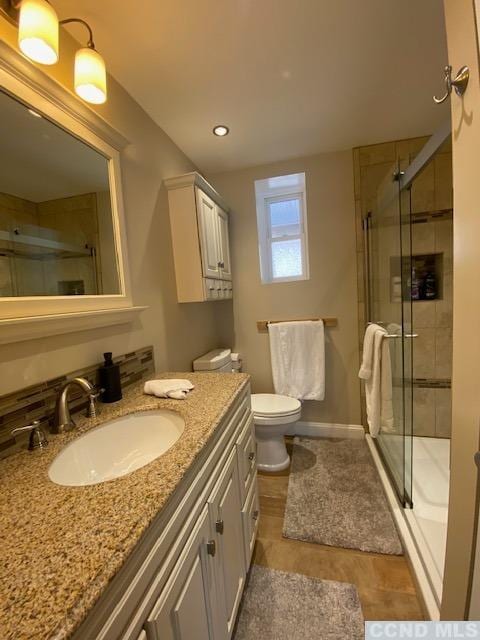 bathroom with tile patterned floors, vanity, toilet, and a shower with shower door