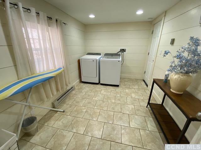 laundry area with separate washer and dryer, wood walls, and a baseboard radiator