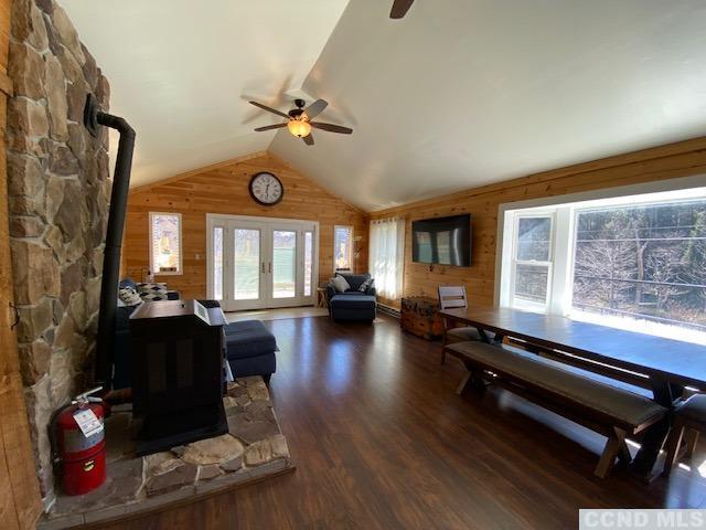 living room featuring wood walls, dark hardwood / wood-style flooring, lofted ceiling, and a wealth of natural light