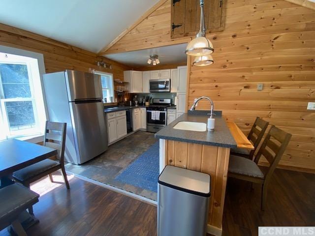 kitchen featuring stainless steel appliances, sink, white cabinets, dark hardwood / wood-style floors, and hanging light fixtures