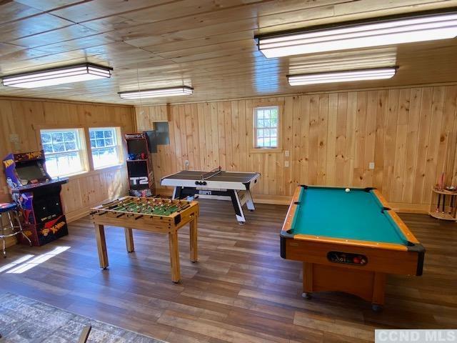 game room featuring pool table, plenty of natural light, dark hardwood / wood-style flooring, and wooden walls