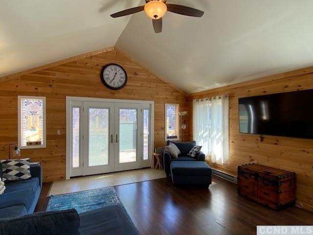 living room with hardwood / wood-style flooring, vaulted ceiling, and wood walls