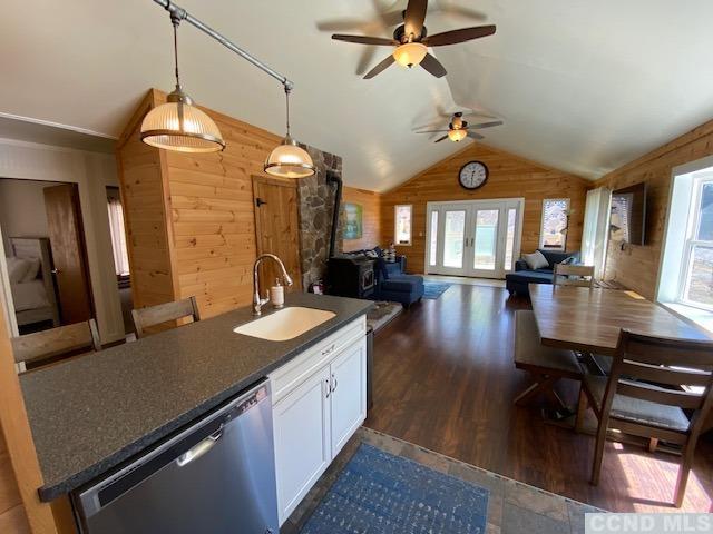 kitchen with white cabinets, plenty of natural light, wood walls, and sink