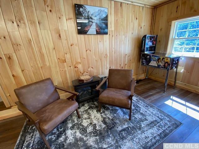 living area featuring hardwood / wood-style flooring and wooden walls