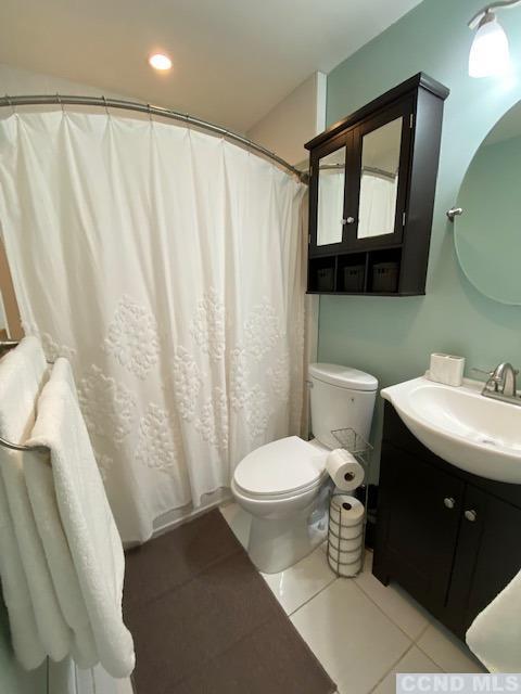 bathroom with toilet, vanity, and tile patterned floors