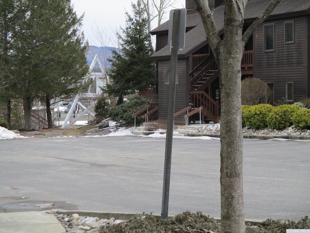 exterior space featuring stairway, a mountain view, and a shingled roof