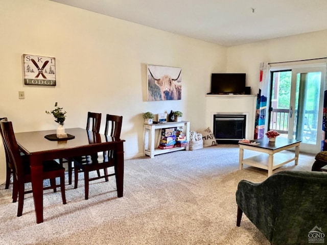 dining space featuring a glass covered fireplace and carpet flooring