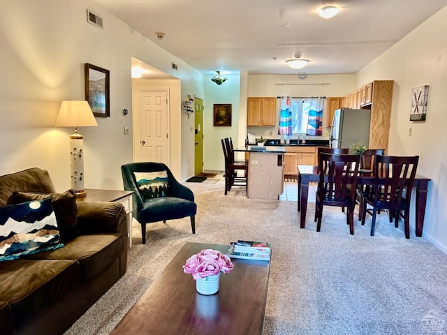 living room featuring visible vents, light carpet, and baseboards