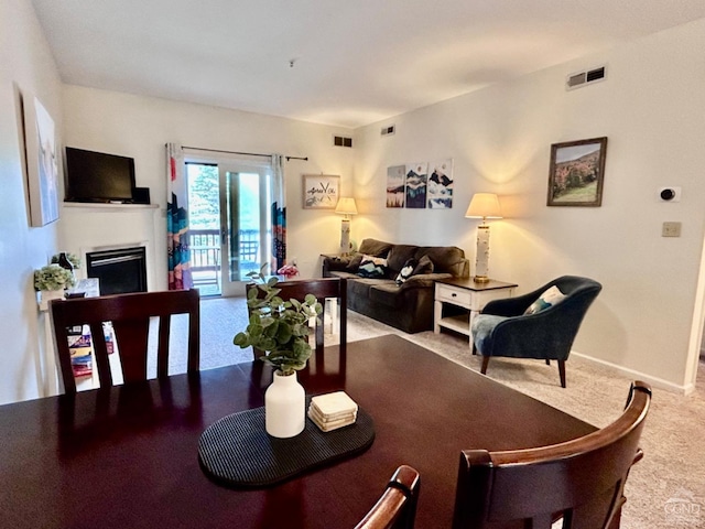 carpeted dining area featuring visible vents, baseboards, and a fireplace