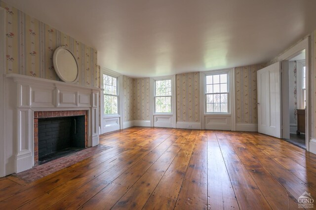 unfurnished living room featuring wallpapered walls, hardwood / wood-style flooring, and a fireplace