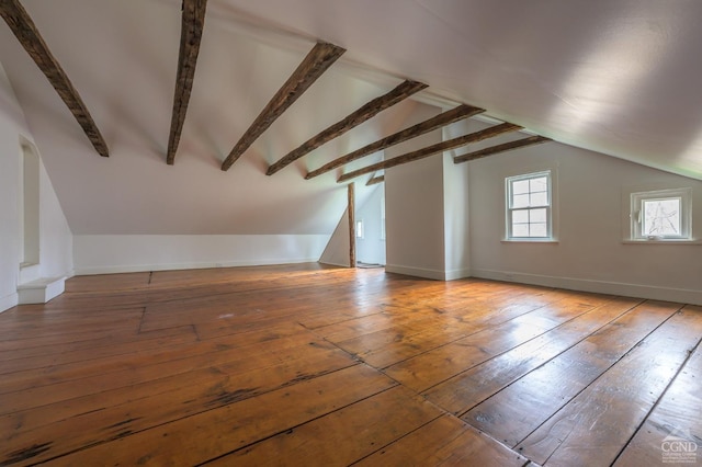 additional living space with hardwood / wood-style floors, baseboards, and vaulted ceiling with beams