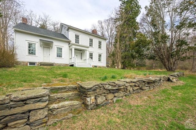 back of property with a chimney and a yard
