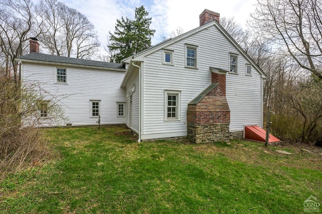 back of property with a chimney and a yard