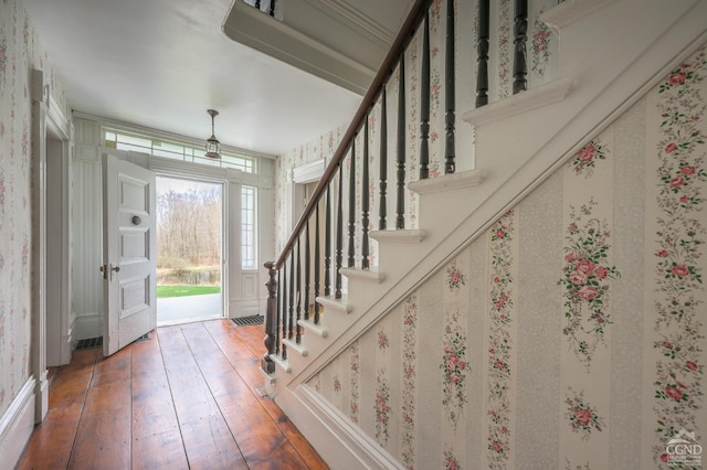 foyer with wood-type flooring, wallpapered walls, and stairway