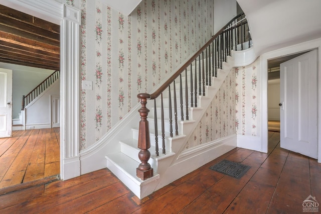 stairs featuring wood-type flooring and wallpapered walls