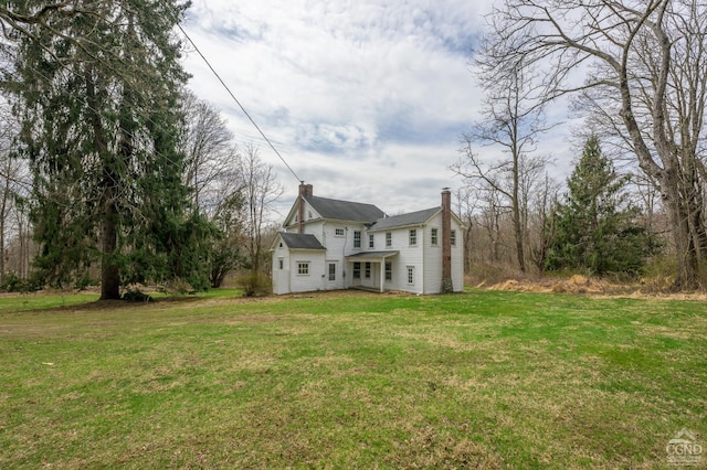back of house featuring a lawn and a chimney