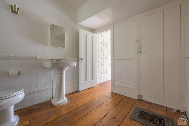 half bathroom with toilet, visible vents, and wood-type flooring