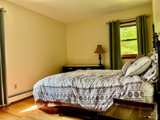 bedroom with baseboard heating and wood finished floors