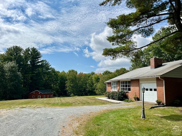 exterior space with a chimney, driveway, brick siding, a garage, and a lawn