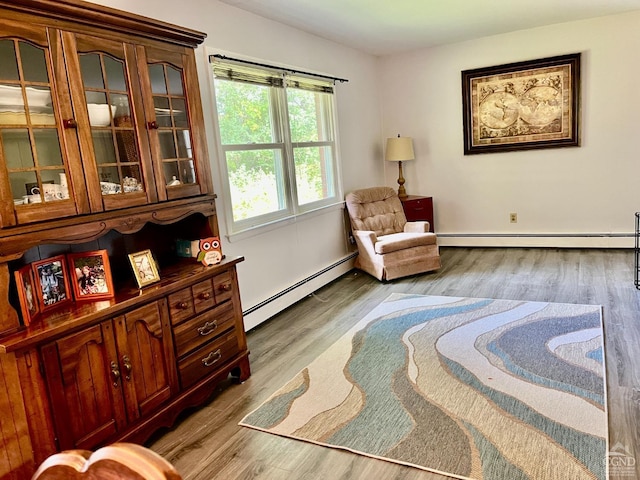 living area with baseboards, a baseboard heating unit, and wood finished floors