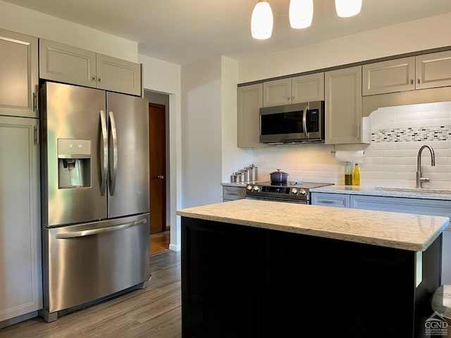 kitchen featuring a sink, backsplash, gray cabinetry, and stainless steel appliances