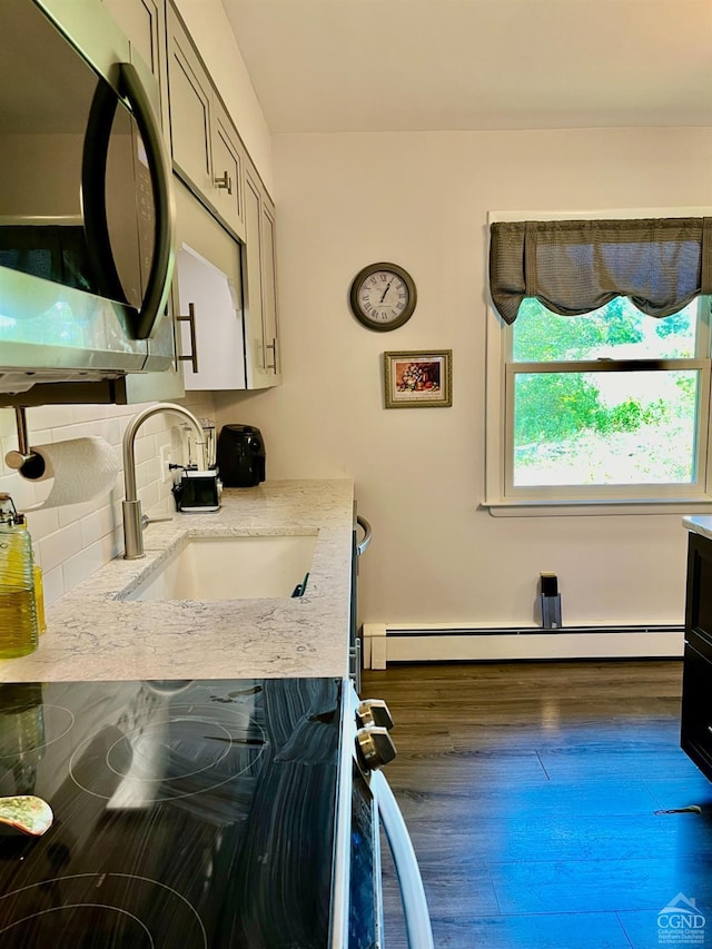 kitchen featuring tasteful backsplash, a sink, baseboard heating, black / electric stove, and light stone countertops