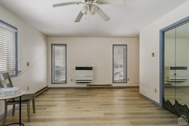 living room featuring light hardwood / wood-style floors, heating unit, and a wealth of natural light