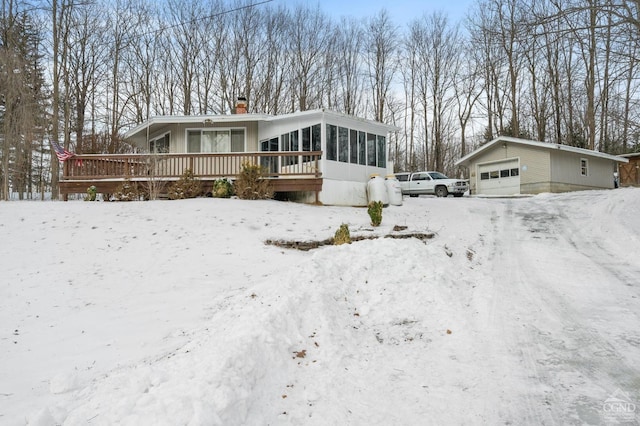 view of front of home with an outbuilding, a garage, a sunroom, and a wooden deck