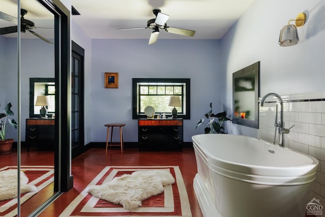 bathroom with a tub to relax in, tile walls, and ceiling fan