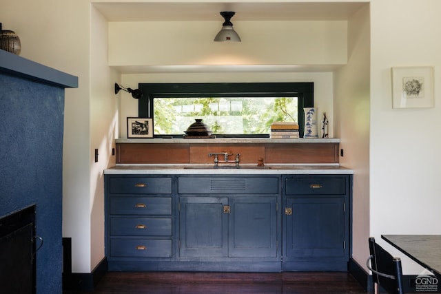 bar featuring blue cabinetry, sink, and dark wood-type flooring