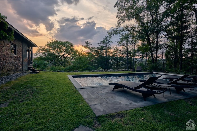 pool at dusk featuring a yard and a patio