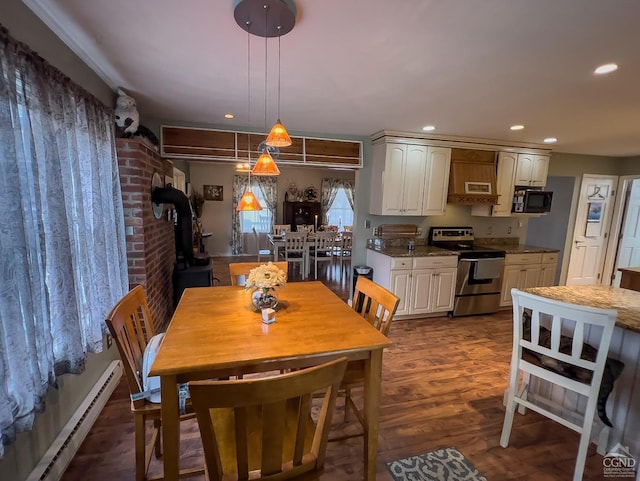 dining room with wood-type flooring, a wood stove, and a baseboard radiator