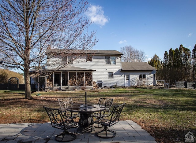 rear view of house with a sunroom, a patio, and a lawn