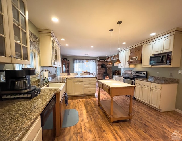 kitchen with black appliances, sink, hanging light fixtures, kitchen peninsula, and brick wall