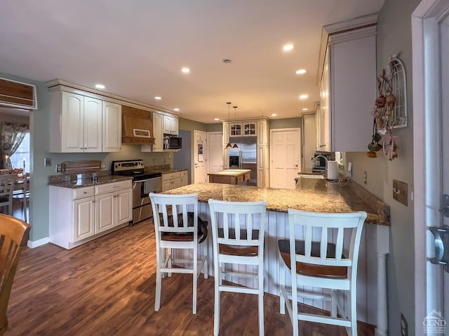 kitchen featuring kitchen peninsula, appliances with stainless steel finishes, dark wood-type flooring, sink, and white cabinetry