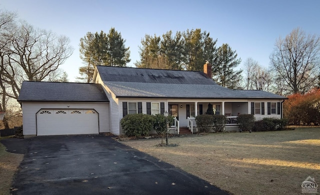 ranch-style home featuring covered porch, a garage, and a front yard