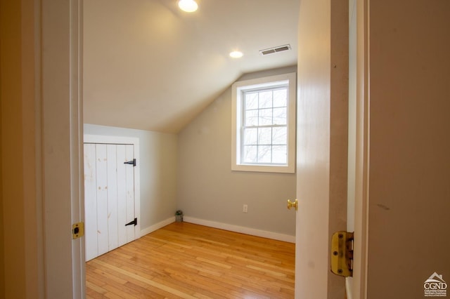 additional living space with light hardwood / wood-style floors and vaulted ceiling