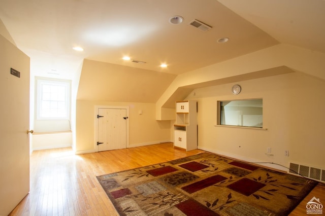 additional living space with hardwood / wood-style flooring and lofted ceiling