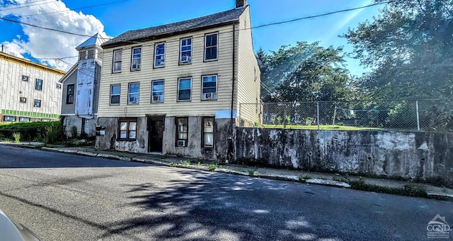 view of front facade with a chimney and fence