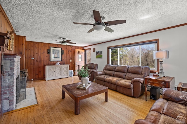 living room featuring a textured ceiling, ornamental molding, a ceiling fan, and light wood-style flooring