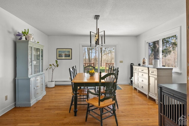 dining room with a healthy amount of sunlight, light wood-style floors, a textured ceiling, and a baseboard radiator